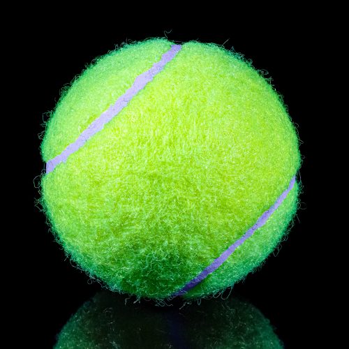 Fluorescent yellow lawn tennis ball on black background